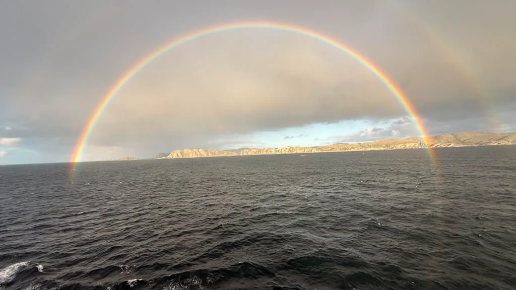A full rainbow on the other side of the sky